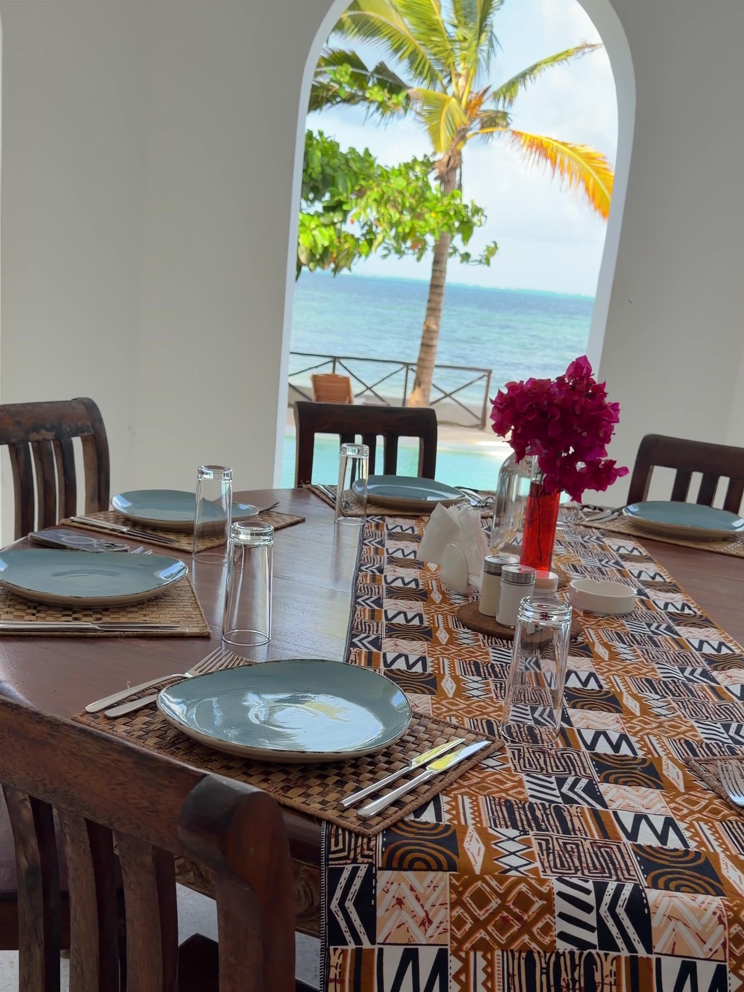 Long dining table set for a group under the arches, ocean view